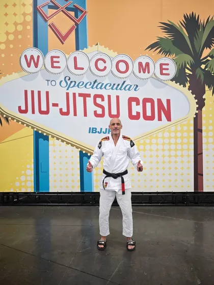 David Gerzain en kimono et ceinture noire devant le panneau Jiu-Jitsu Con à Las Vegas